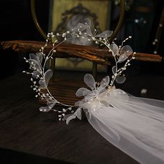 a white bridal headpiece with flowers and pearls on it sitting on a table