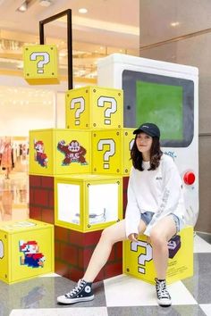 a woman sitting on top of blocks in front of a game machine with question marks