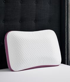 a close up of a pillow on a bed with a headboard in the background