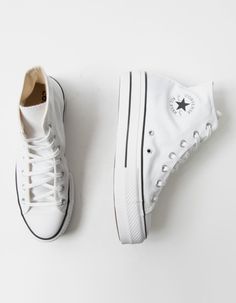 two pairs of white converse shoes sitting on top of a white table next to each other