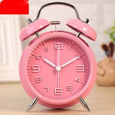 a pink alarm clock sitting on top of a table