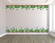 an empty room with wood flooring and green squares painted on the wall behind it