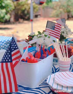 a patriotic table setting with plates, cups and utensils for an outdoor party