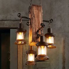 a chandelier with five lights hanging from it's sides and an old wooden door in the background