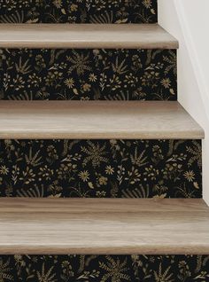 the stairs are painted with black and gold floral wallpaper, along with a wooden handrail