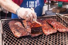 a man is grilling ribs on the grill with tongs and an object in his hand