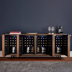 a wine cooler with several bottles and glasses on it in front of a gray wall