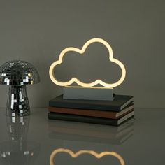 a cloud shaped lamp sitting on top of a table next to a stack of books