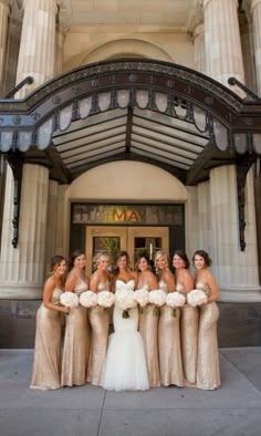 a group of women standing next to each other in front of a building holding bouquets