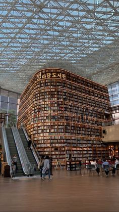 people are walking through the library with an escalator and stairs in front of them