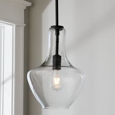 a clear glass light fixture hanging from a ceiling in a room with white walls and windows