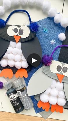 two penguins made out of construction paper and pom poms