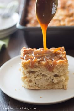 a spoon drizzling caramel sauce on top of a piece of cake