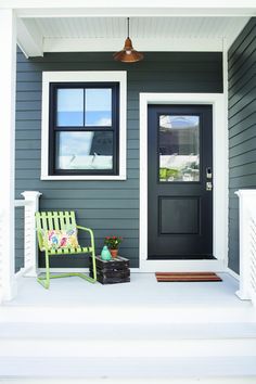 the front door of a house with a green bench on the porch next to it