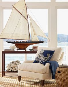 a living room filled with furniture and a sailboat on top of a table in front of large windows