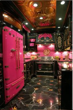 a kitchen with pink appliances and black counter tops, gold accents on the ceiling and floor