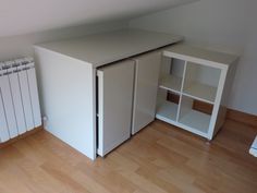 a small white cabinet sitting next to a radiator in a room with hard wood floors