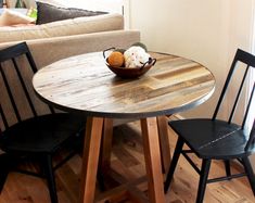 a small table with two chairs around it and a bowl of fruit on the table