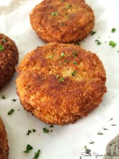 three crab cakes sitting on top of a white paper towel next to some parsley