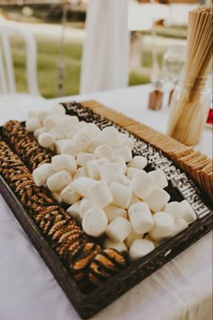 marshmallows are arranged on a platter at an outdoor wedding reception table