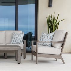 two chairs and a coffee table sitting on a patio next to a large glass window