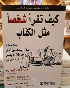 a sign with arabic writing on it in front of stacks of folded books at a store