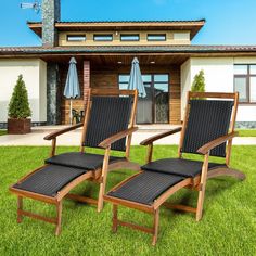 two lawn chairs sitting in the grass with blue umbrellas