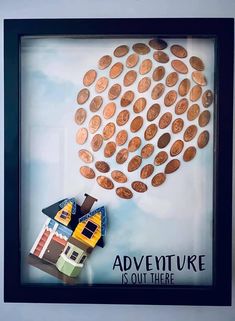 a frame with some coins on it and a house in the middle that says adventure is out there