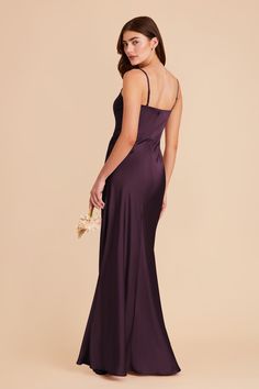 a woman in a long purple dress is looking back at the camera and she has her hand on her hip