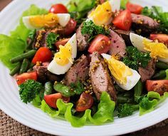 a salad with meat, eggs and vegetables on a white plate - stock image /