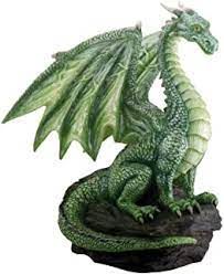 a green dragon statue sitting on top of a rock