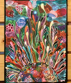 a colorful painting on wood with lots of different colors and shapes in the background,