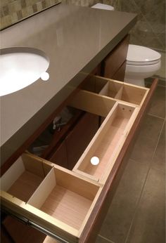 an open drawer in the middle of a bathroom counter next to a toilet and sink