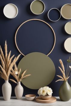 vases with flowers and plants in front of a blue wall decorated with circular mirrors