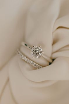 a diamond ring sitting on top of a white satin material with diamonds in the middle