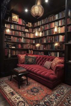 a red couch sitting in front of a bookshelf filled with lots of books