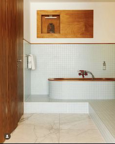 a bathroom with white tile and wood accents