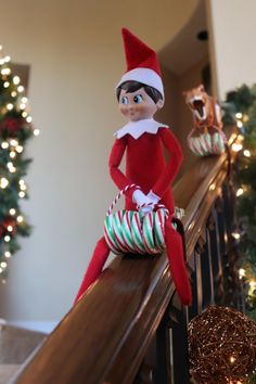 an elf sitting on top of a banister next to christmas decorations