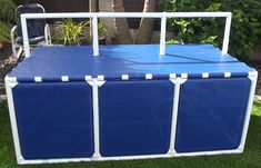 a blue and white cooler sitting on top of green grass next to a palm tree