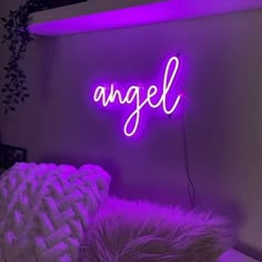 a purple neon sign that says angel on the side of a wall above a bed