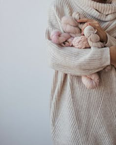 a woman in a sweater holding several baby animals