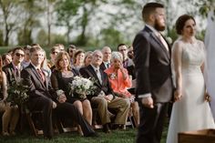 a bride and groom standing at the end of their wedding ceremony in front of an audience