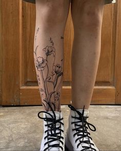 a woman's legs with flowers on them and black laces around the ankles