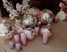 candles and disco balls are arranged on the floor next to each other in front of flowers