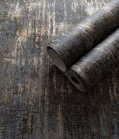 two rolled up rugs sitting on top of a carpet covered in brown and black colors