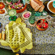 a table topped with plates and bowls filled with food next to utensils on top of a cloth