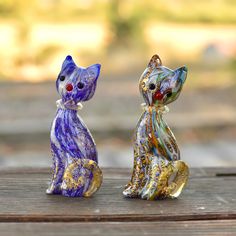 two glass cats sitting on top of a wooden table