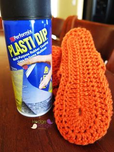 an orange knitted mitt next to a can of plastic dip on a table