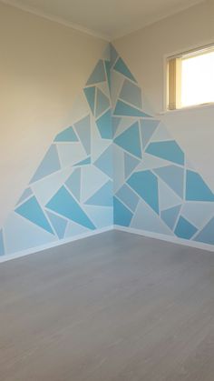 an empty room with blue triangles painted on it's walls and wood flooring