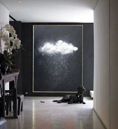 a dog laying on the floor in front of a black wall with white clouds painted on it